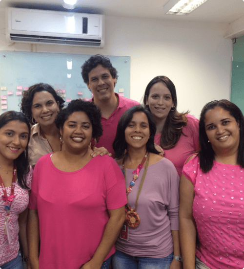 Imagem de colaboradoras da Pitang sorrindo vestidas com roupas na cor rosa