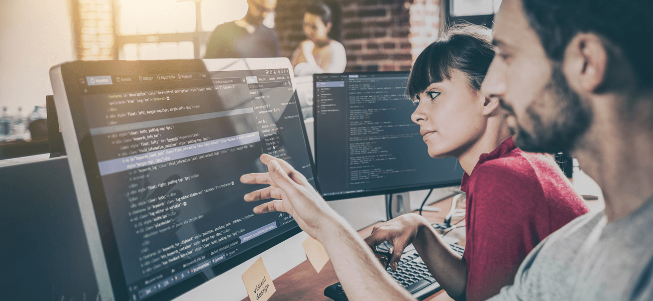 Homem e mulher olhando para a tela de um computador com código código-fonte